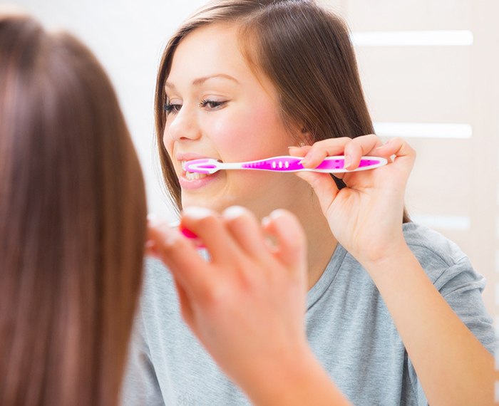 Teen brushing her teeth in bathroom at home