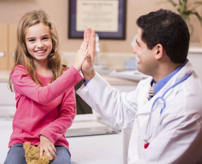 Young girl smiling and giving her dentist a high five