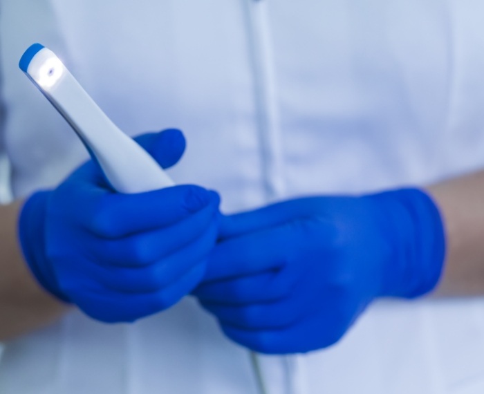 Dental team member holding thin white intraoral camera