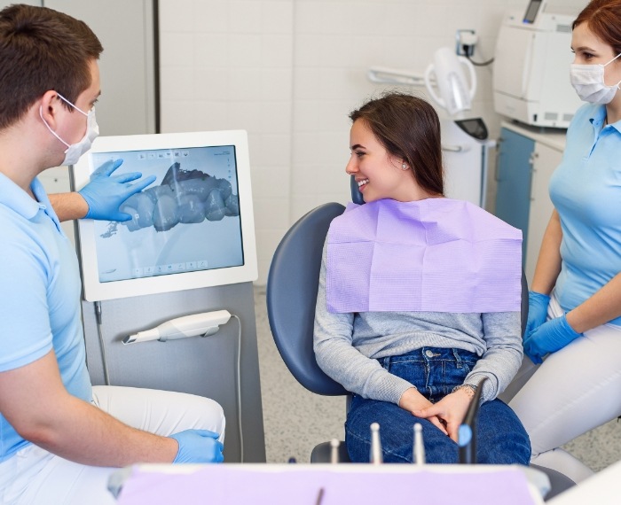 Dentist showing a young girl in dental chair her dental x rays