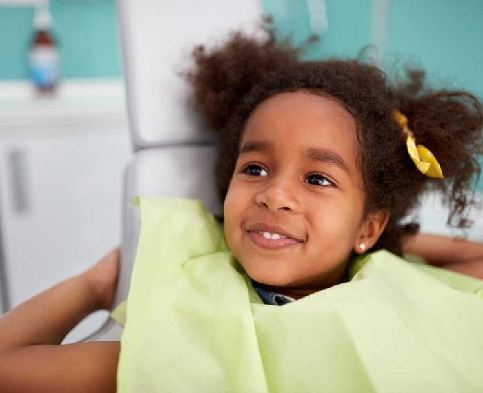 Child in dental chair smiling at her dentist