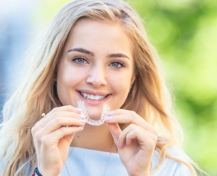 Young woman putting clear aligner into her mouth