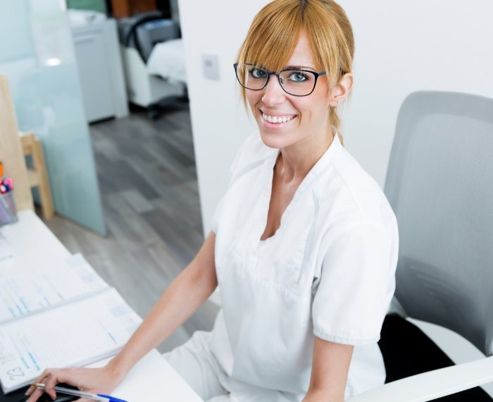 Smiling dental team member sitting at desk