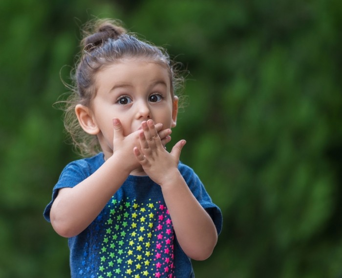 Young girl covering her mouth with both hands