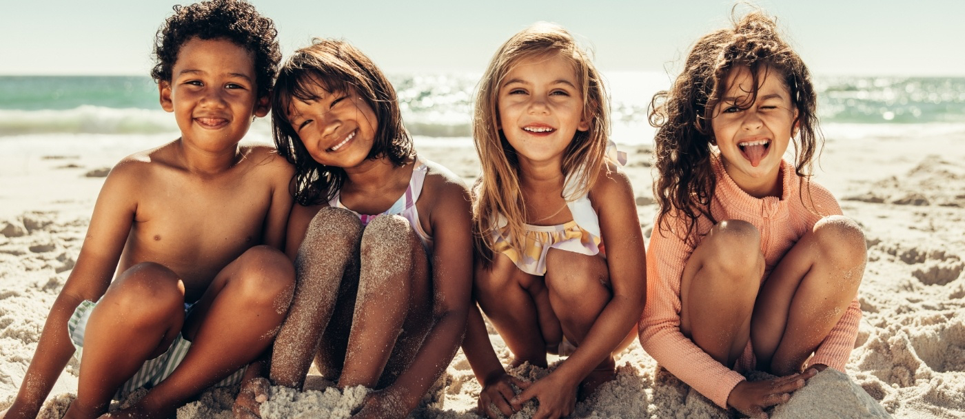 Four children smiling at the beach after visiting Pleasanton pediatric dentist