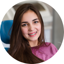 Teenage girl with braces smiling in dental chair