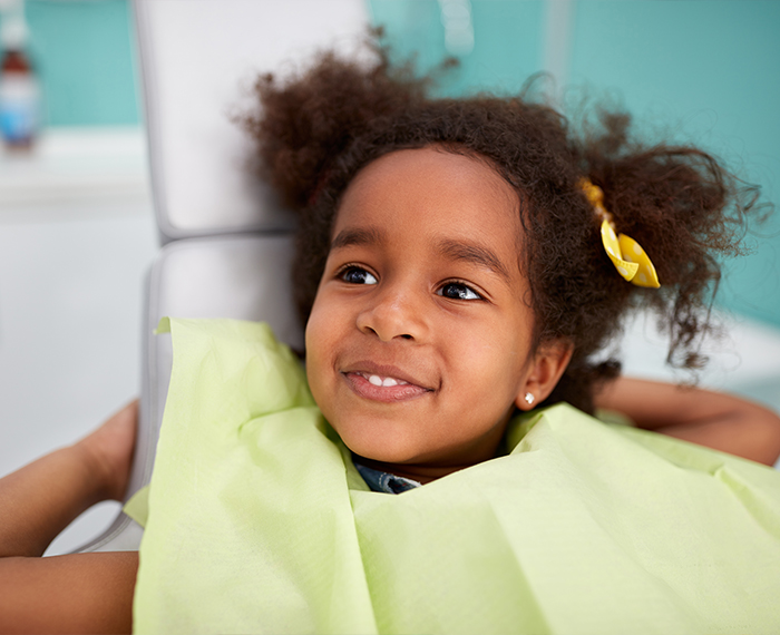 Young girl in dental chair smiling at her dentist