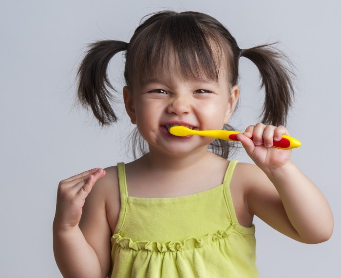 Young girl with pigtails brushing her teeth