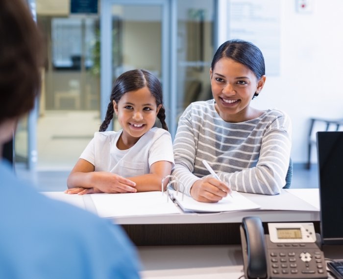 Mother and daughter at dental office front desk