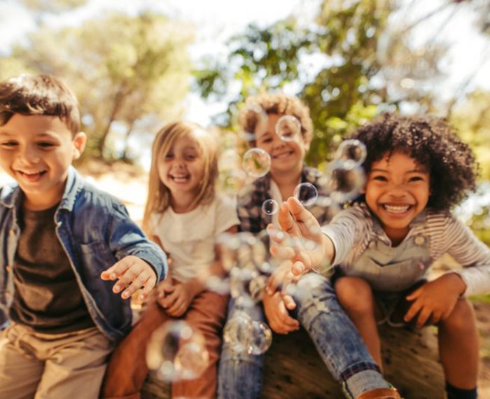 Happy group of kids playing outside with bubbles