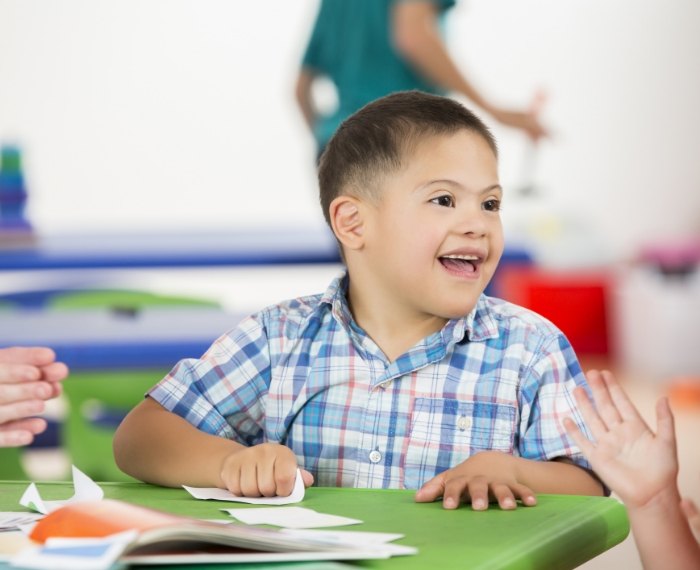 Smiling young boy sitting at desk in classroom