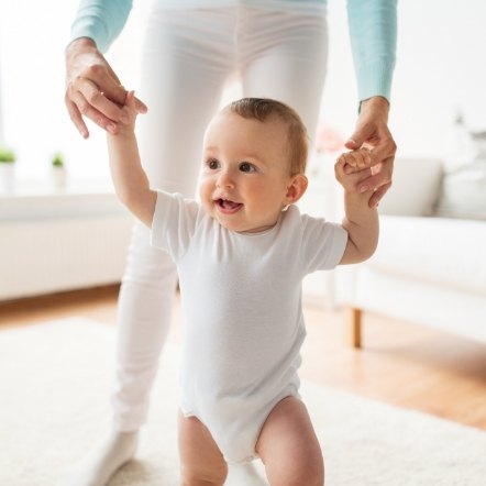 Parent helping their toddler walk